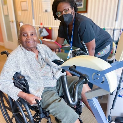 Resident exercising with staff in an activity room