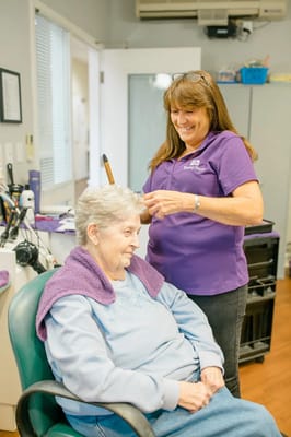 Staff member styling a resident's hair in a salon