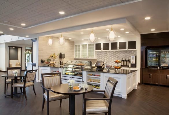 Bright dining area with a bakery display and seating