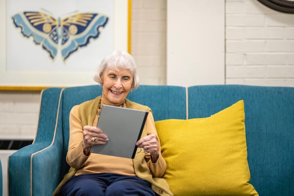 Senior resident enjoying a tablet in a cozy common area