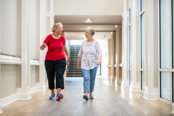 Two residents walking together in a bright hallway