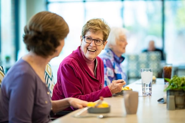 Residents sharing a meal and laughing in the dining area