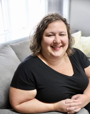 A smiling staff member seated on a couch
