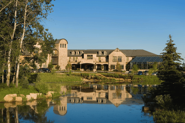 Exterior view of a senior living facility reflected in a pond