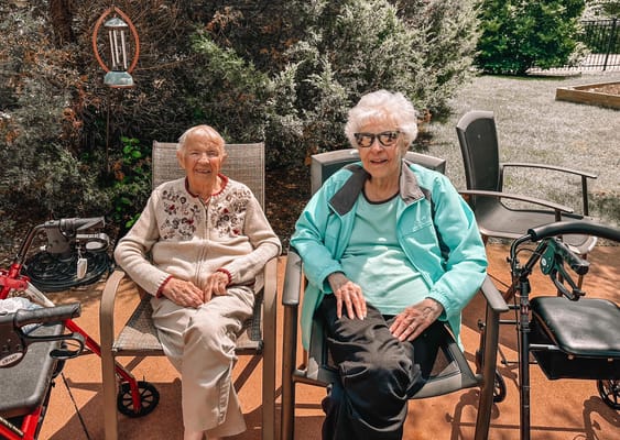 Two residents sitting outdoors in a garden area