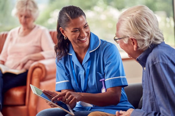 Staff member assisting a resident with a tablet