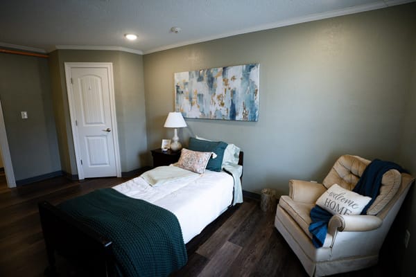 A private room featuring a bed and armchair