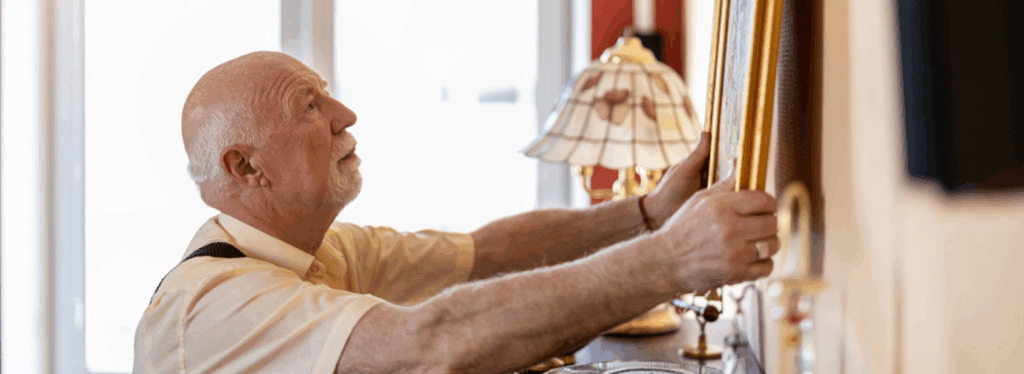 Senior resident adjusting a picture frame indoors