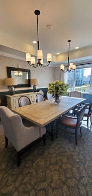 Bright dining room with a long wooden table and floral arrangement