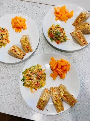 Three plates of food including sandwiches and fruit