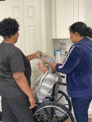 Two staff members styling a resident's hair