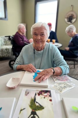 A senior resident participating in an art activity in a common area
