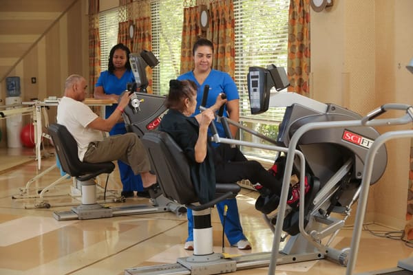 Residents engaging in physical therapy exercises with staff assistance