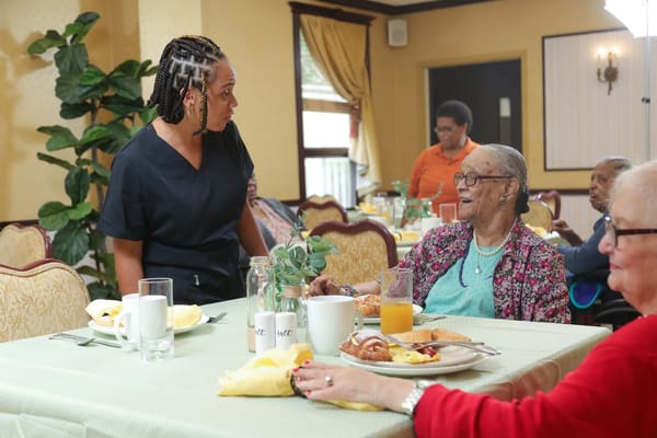 Residents enjoying a meal with staff in the dining room