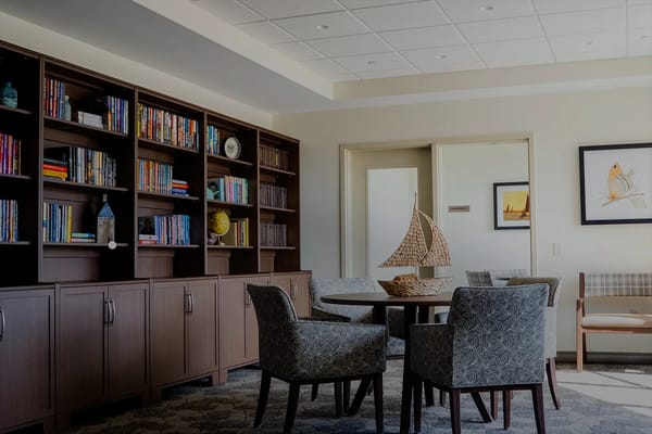 Lounge area with bookshelves and seating in TLC Assisted Living.