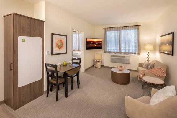 Inviting living room with seating and dining area in TLC Assisted Living facility.