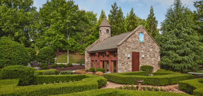Stone chapel building surrounded by manicured gardens