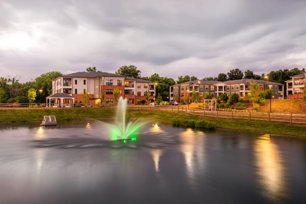 Scenic pond with fountain in front of residential buildings
