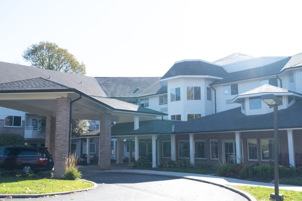 Main entrance of Independence Village of Des Moines featuring a canopy and parking area.