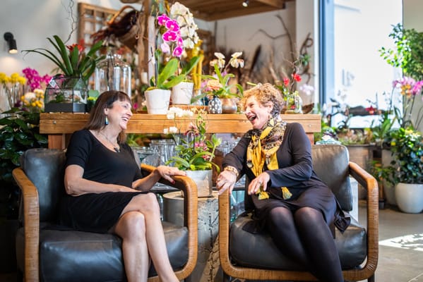 Two women joyfully conversing in a floral shop
