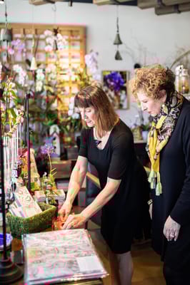 Two women engaged in a floral arrangement activity indoors