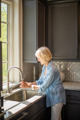 Resident washing hands at a kitchen sink