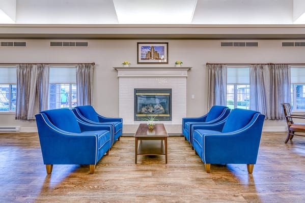 Bright common area with blue chairs and fireplace