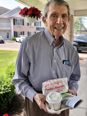 Elderly man enjoying donuts and coffee outside