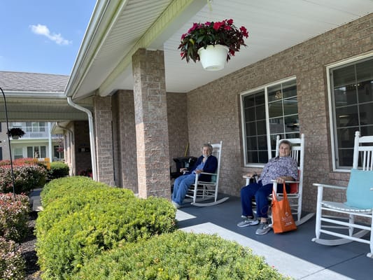 Residents relaxing on rocking chairs in a garden area