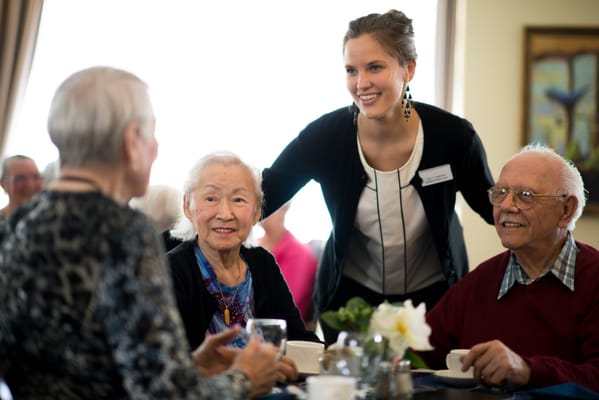 Residents enjoying coffee with a staff member in a common area