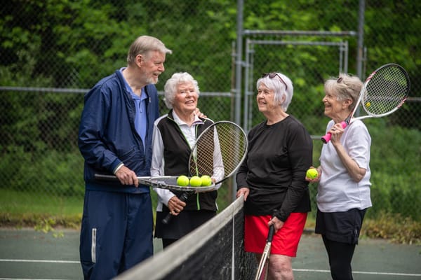 Seniors enjoying a game of tennis in a green outdoor setting