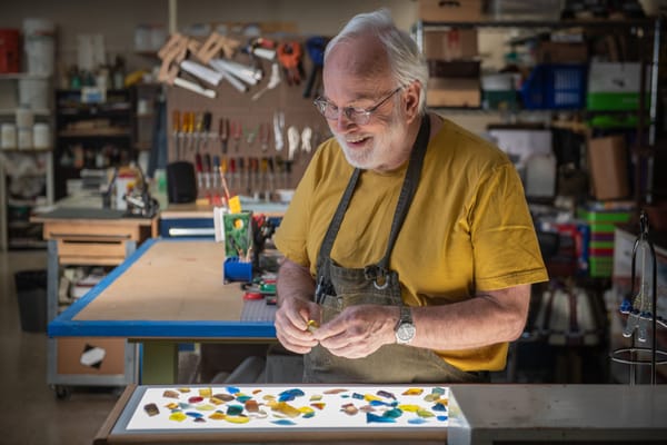 An elderly man engaged in a craft activity in a workshop