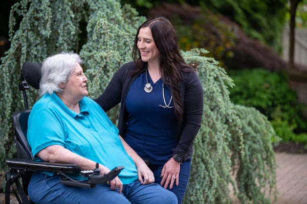 A resident smiling with a staff member in an outdoor garden