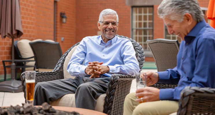 Two seniors enjoying conversation on a patio outside