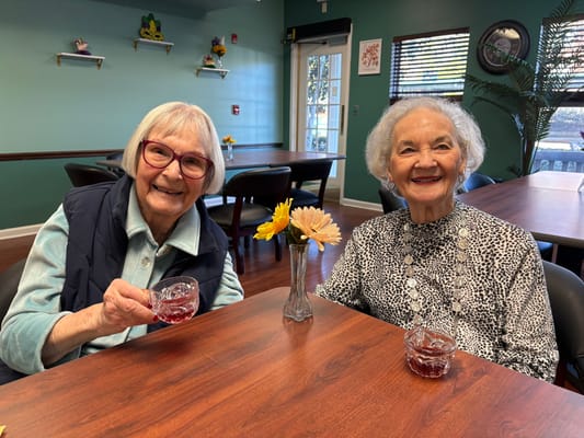 Two residents smiling with drinks in common area
