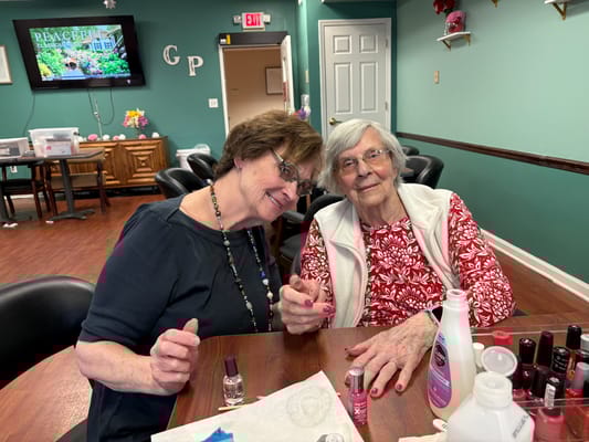 A staff member and resident enjoying a manicure in a common area
