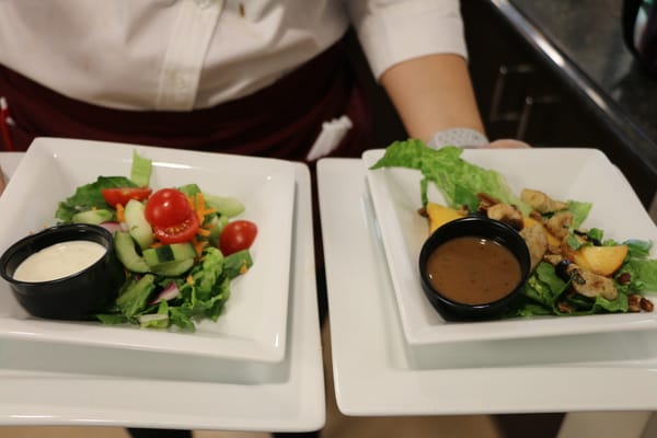Diner serving two beautifully plated salads