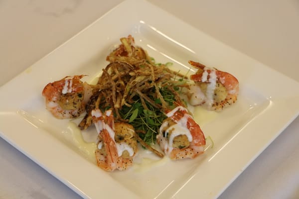 Plated gourmet shrimp dish with greens and crispy garnish