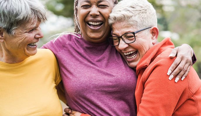 Three women laughing together outdoors
