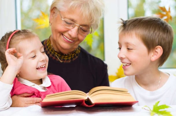 A senior woman reading with two laughing children