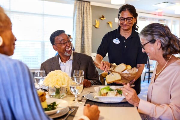Residents enjoying a meal with staff in a dining room