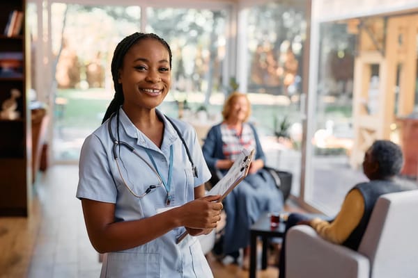 A nurse smiling while holding a clipboard in a bright common area