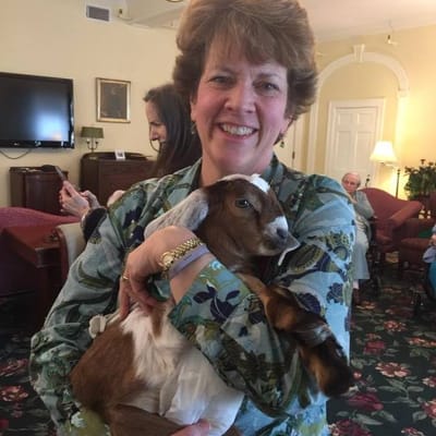 Resident holding a goat during a community visit