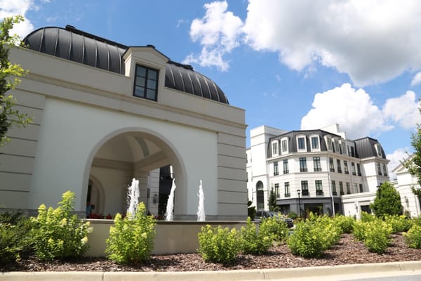 Exterior view of a senior living facility with gardens and fountains