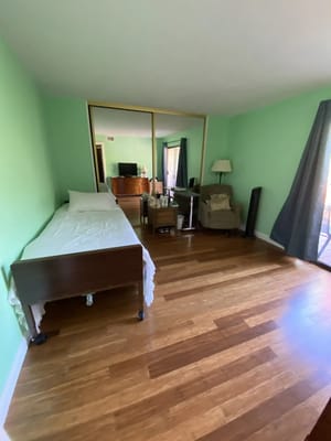 Spacious resident room with green walls and wooden floor