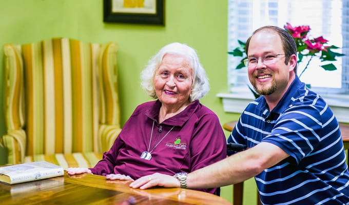 A resident and staff member smiling in an interior room