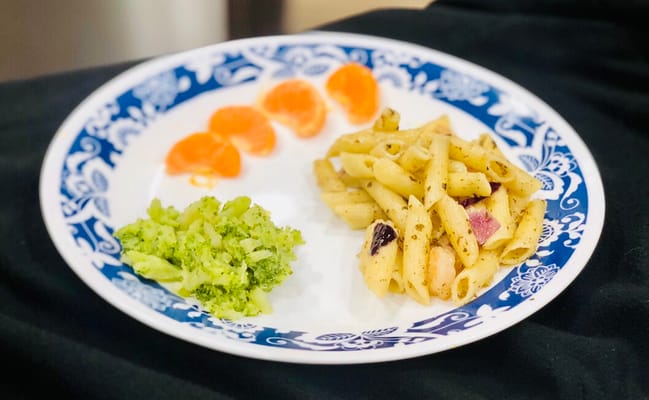 A plate of food including pasta, broccoli, and oranges