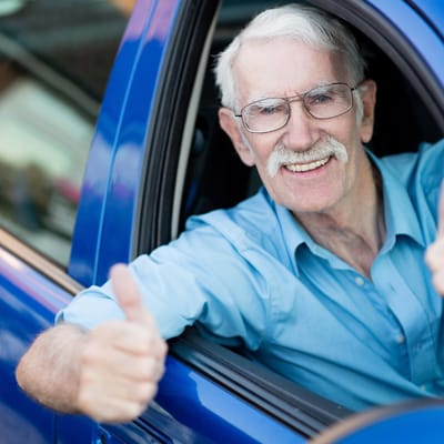 Senior man giving a thumbs up from a vehicle