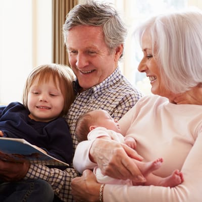 Grandparents reading with grandchildren in a cozy living room