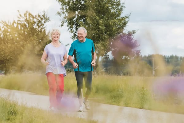 An elderly couple jogging together in a park